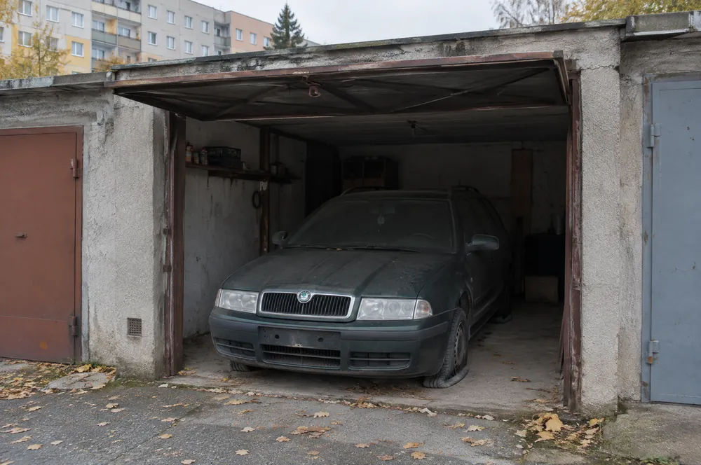 Zaprášená tmavě zelená Škoda Octavia stojí roky v řadové garáži u sídliště v Hostivaři